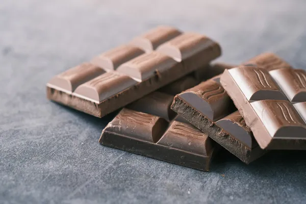 Carrés de chocolat noir cassés, posés sur une surface en pierre