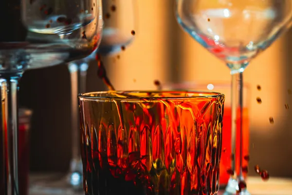 Verres à vin et à whisky éclairés d'une lumière chaude, sur une table